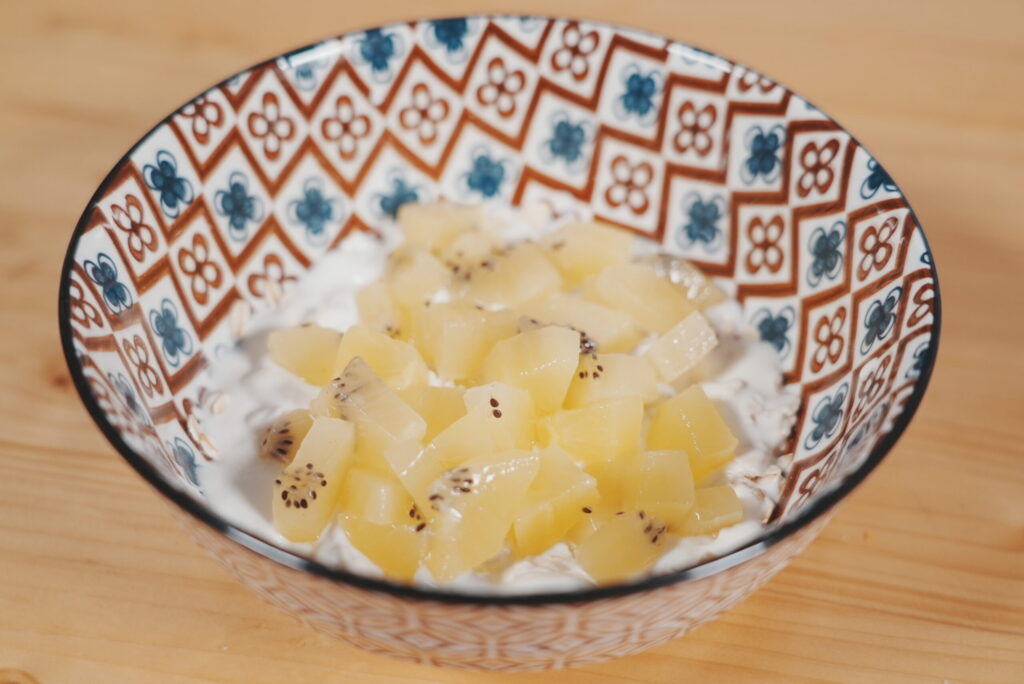 Bol de kéfir con copos de avena, adornado con trozos de piña y kiwi.