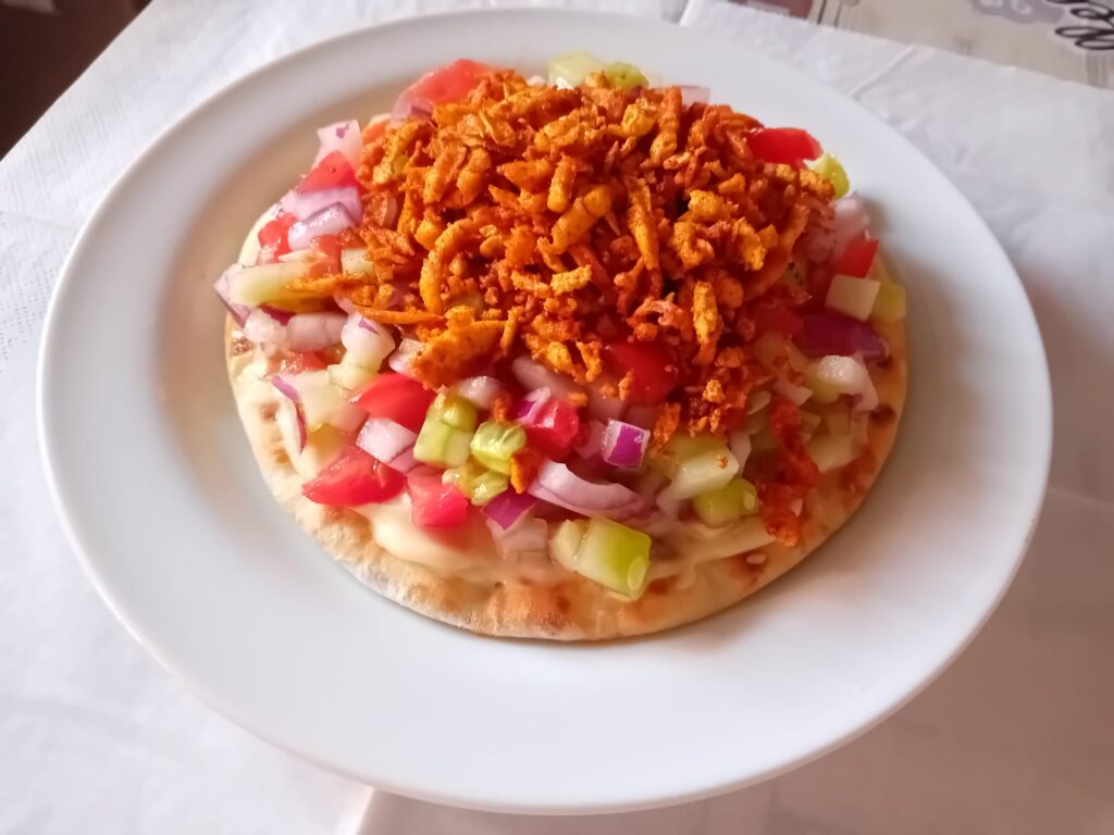 Pan de pita con verduras frescas (tomate, cebolla y pepino) y tofu crujiente por encima.