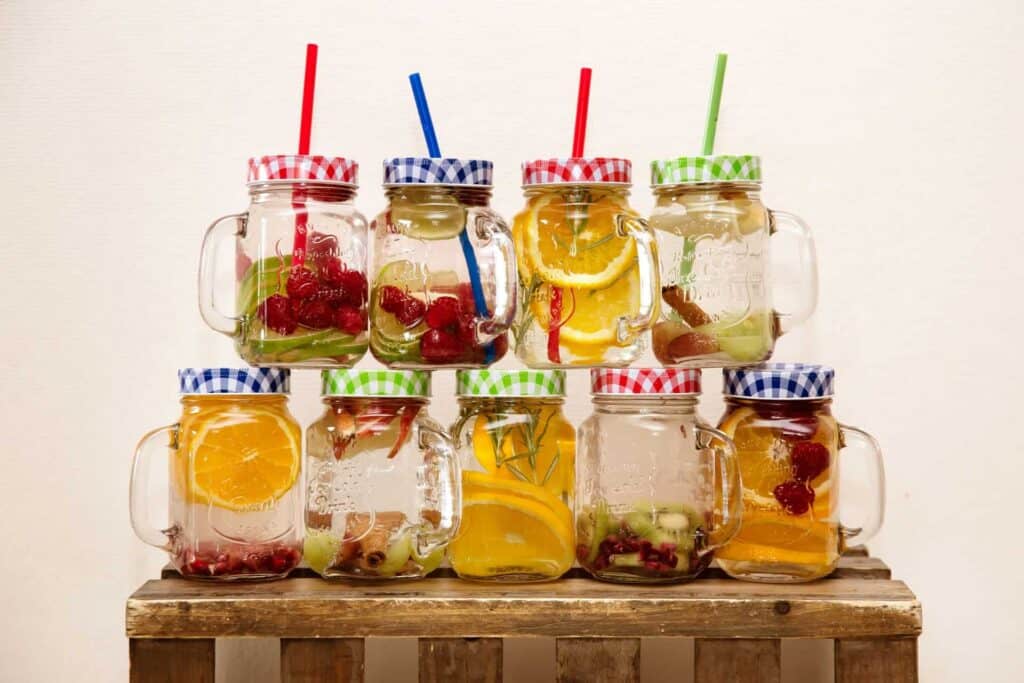 Tarros de cristal con pajitas que contienen agua aromatizada.