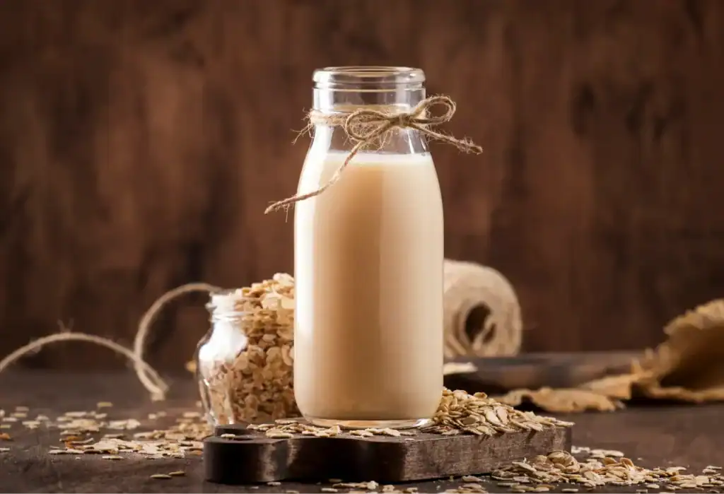 Botella de leche de avena casera junto a copos de avena, batido natural recomendado para el estreñimiento
