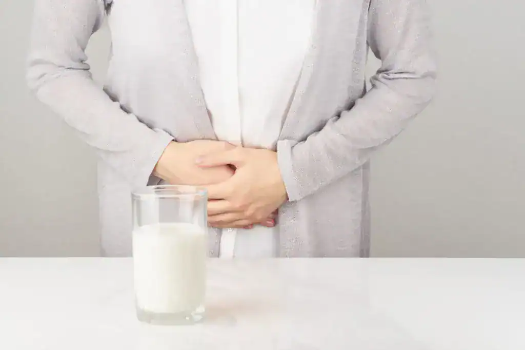 Vaso de leche y persona con molestia abdominal