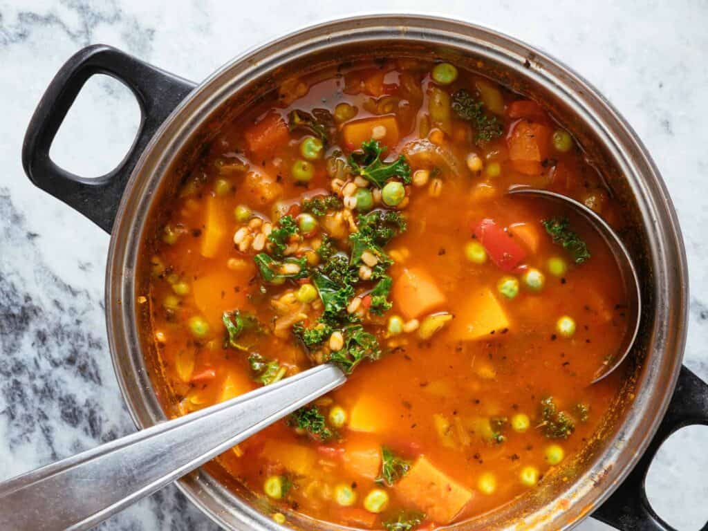 Olla de sopa de verduras con calabaza, guisantes, col rizada y cebada, una receta de aprovechamiento.